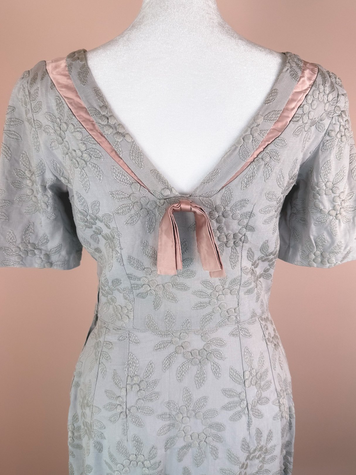 Slate blue 1950s women’s dress featuring textured floral embroidery and a satin bow at the back neckline.