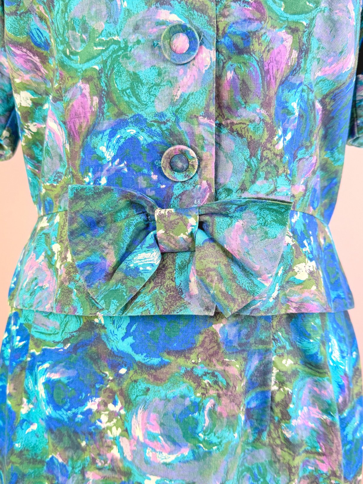 1950s women's skirt set in blue with a floral pattern and bow detail at the waist.