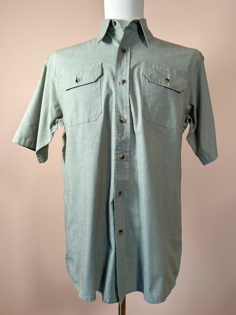 Sage green short-sleeve camp shirt for men from Wrangler Authentics, featuring two front pockets and a button-down front.