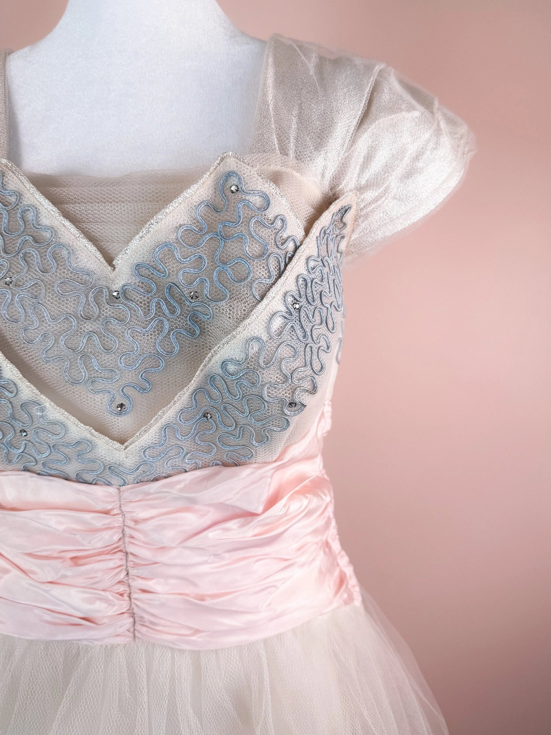 Light pink dress with a sequined blue design on the bodice and sheer puff sleeves.
