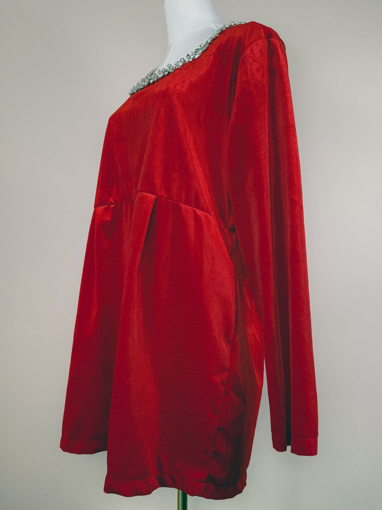 Red velvet dress with long sleeves and a marquise diamond-embellished neckline, styled for women in the 1970s.