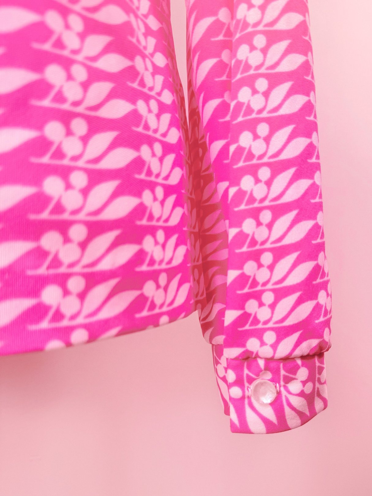Pink 1970s women's blouse featuring a cherry petal pattern and buttoned sleeve.