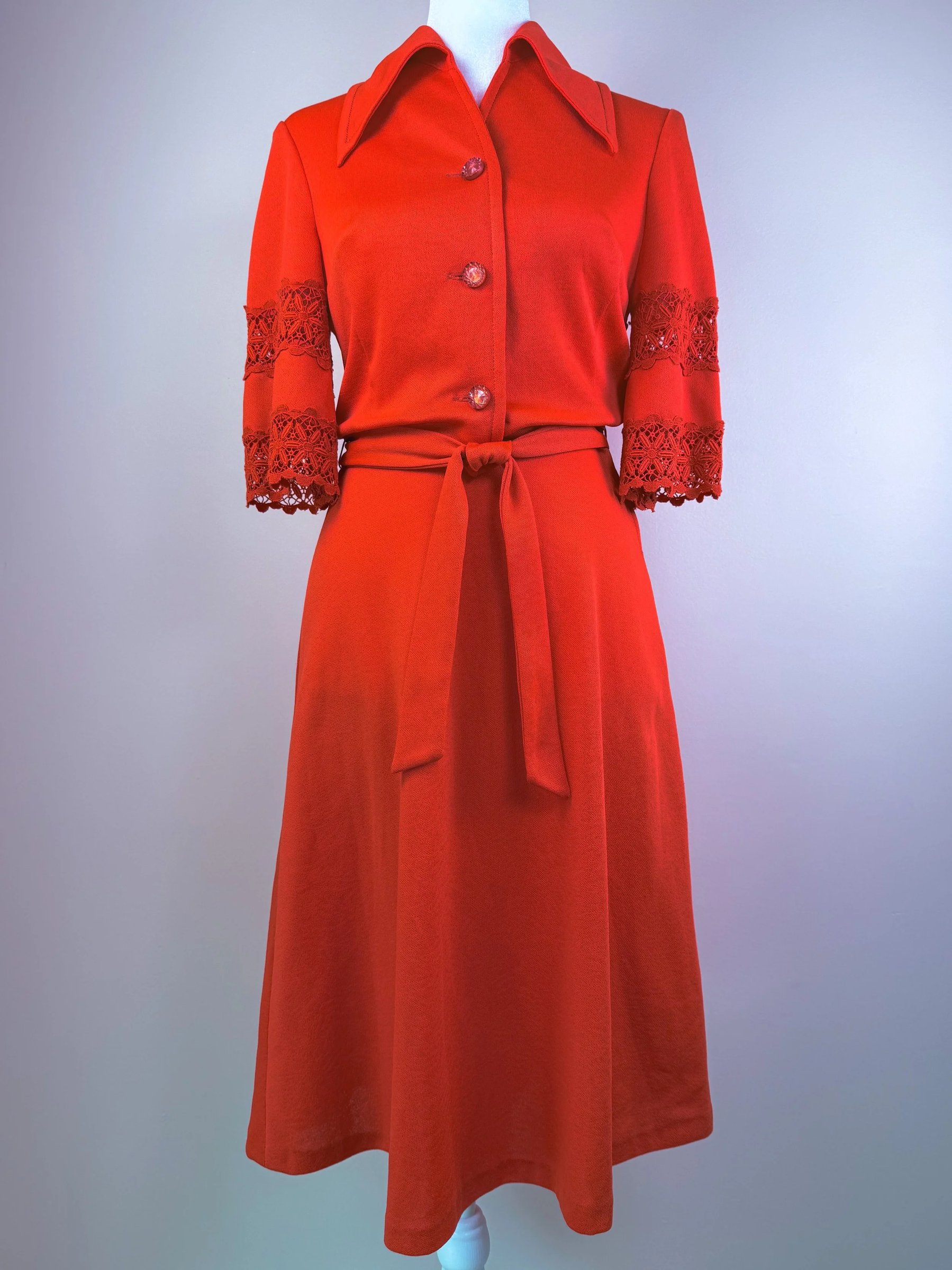 A red dress with a fitted waist, button-up front, and lace detail on the sleeves.