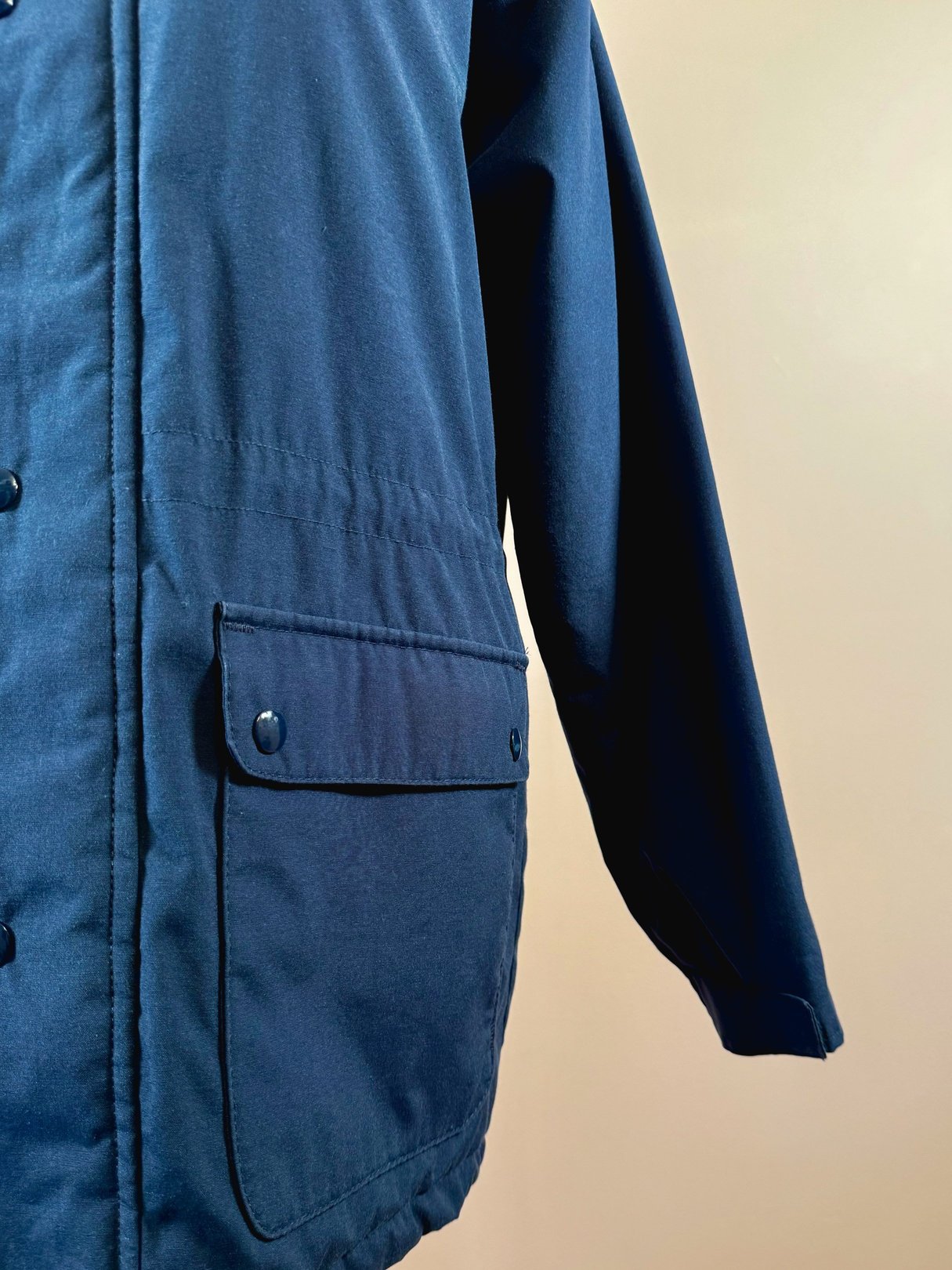 Navy blue 1970s women's utility field coat featuring a button closure and a patch pocket on the front.