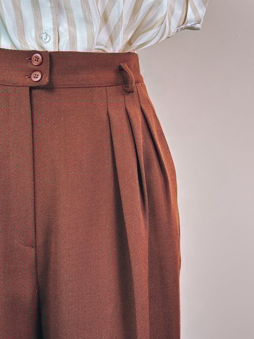 Chestnut-colored women's 1990s trousers featuring a pleated front and two-button waistband.