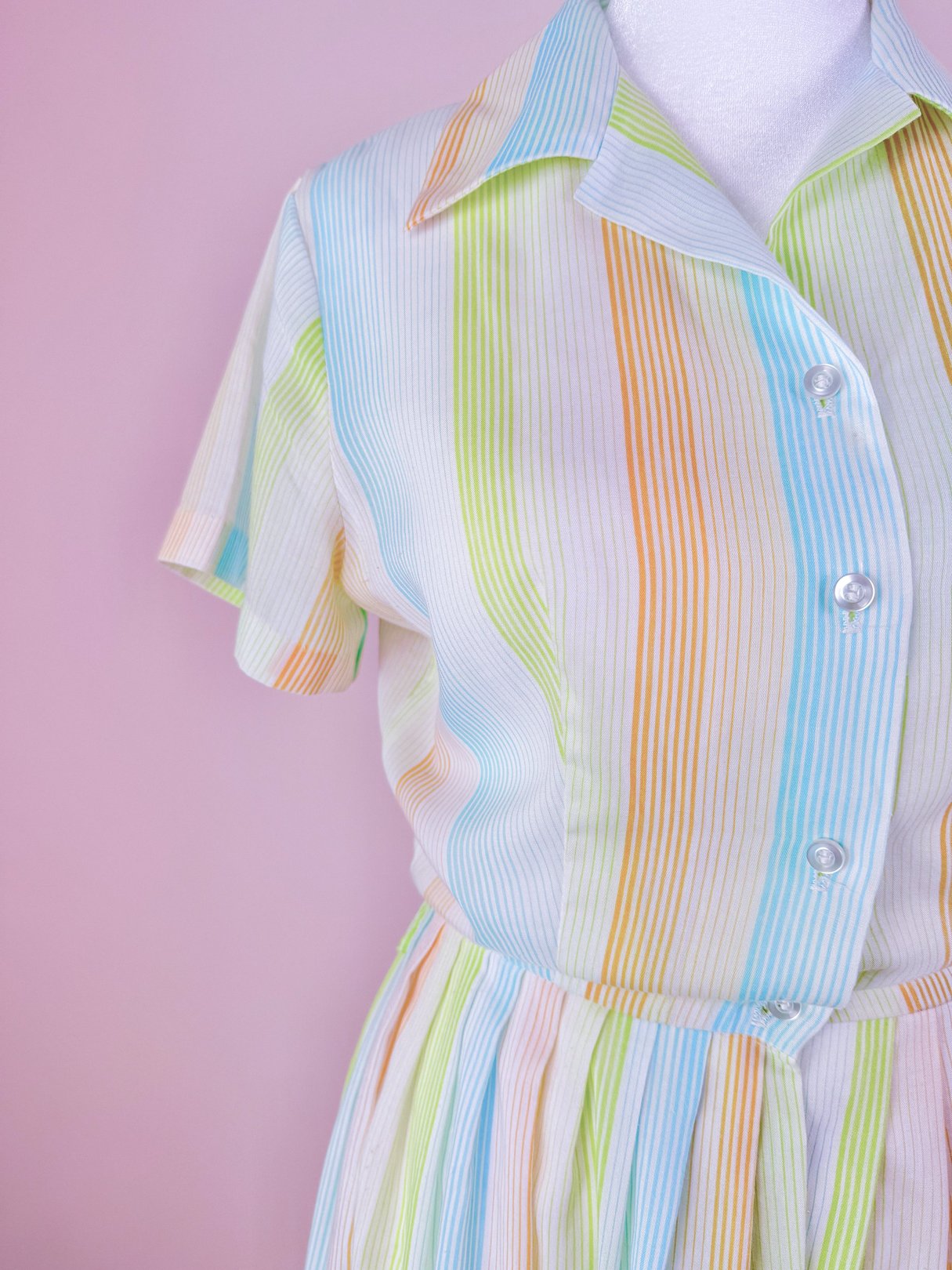 1950s women's dress featuring horizontal stripes in orange, green, blue, and white with a collared neckline and short sleeves.