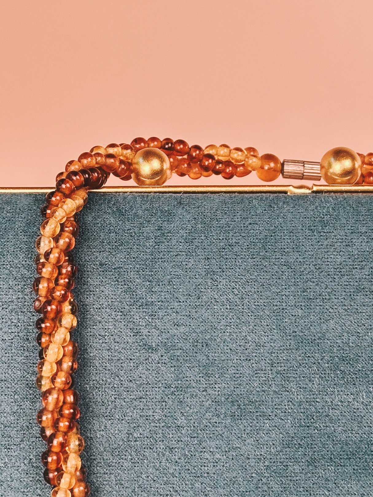 Amber Harvest Beaded Necklace with various shades of amber beads and a gold clasp, displayed against a textured background.