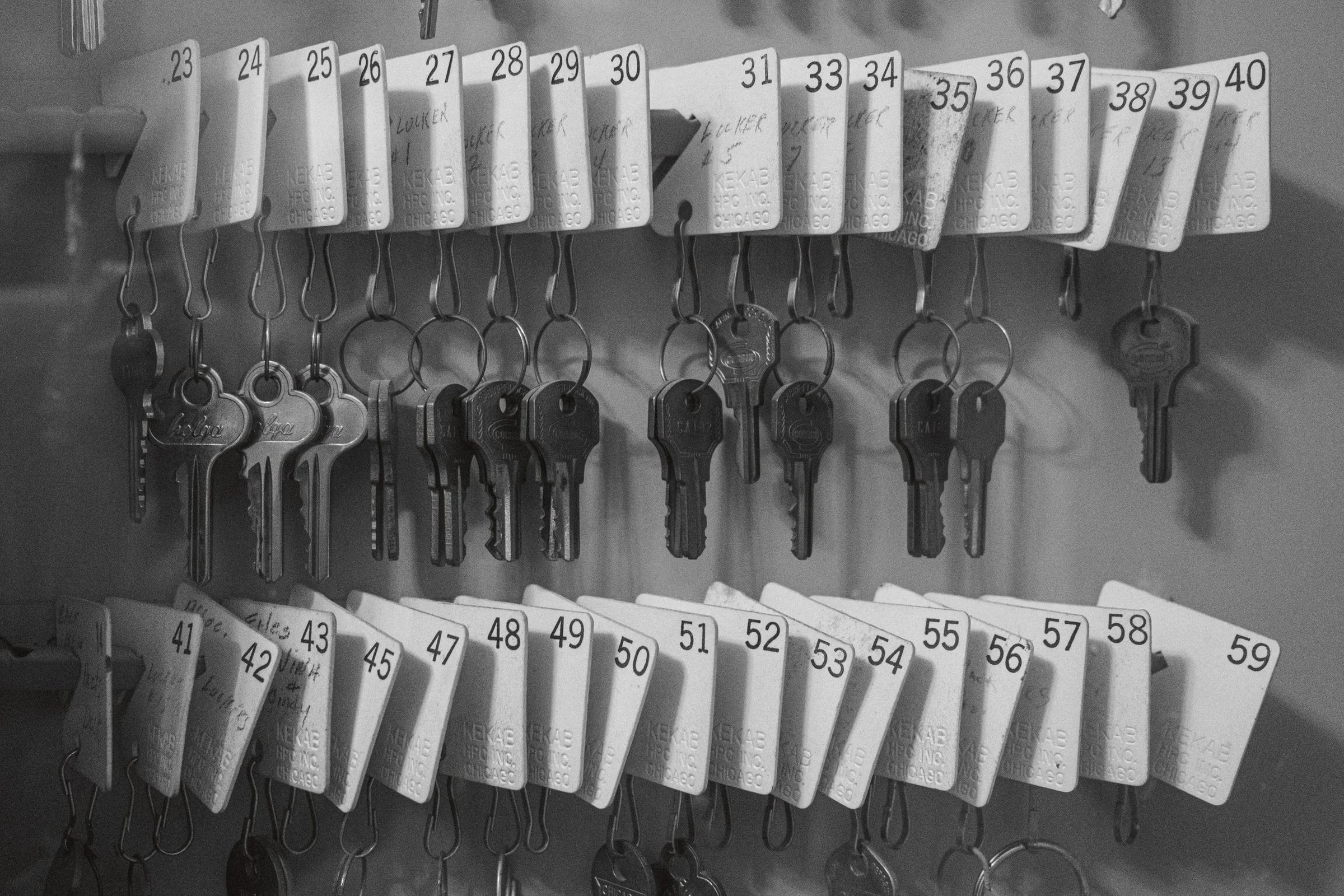 A collection of numbered keys hanging on a wall with corresponding tags.