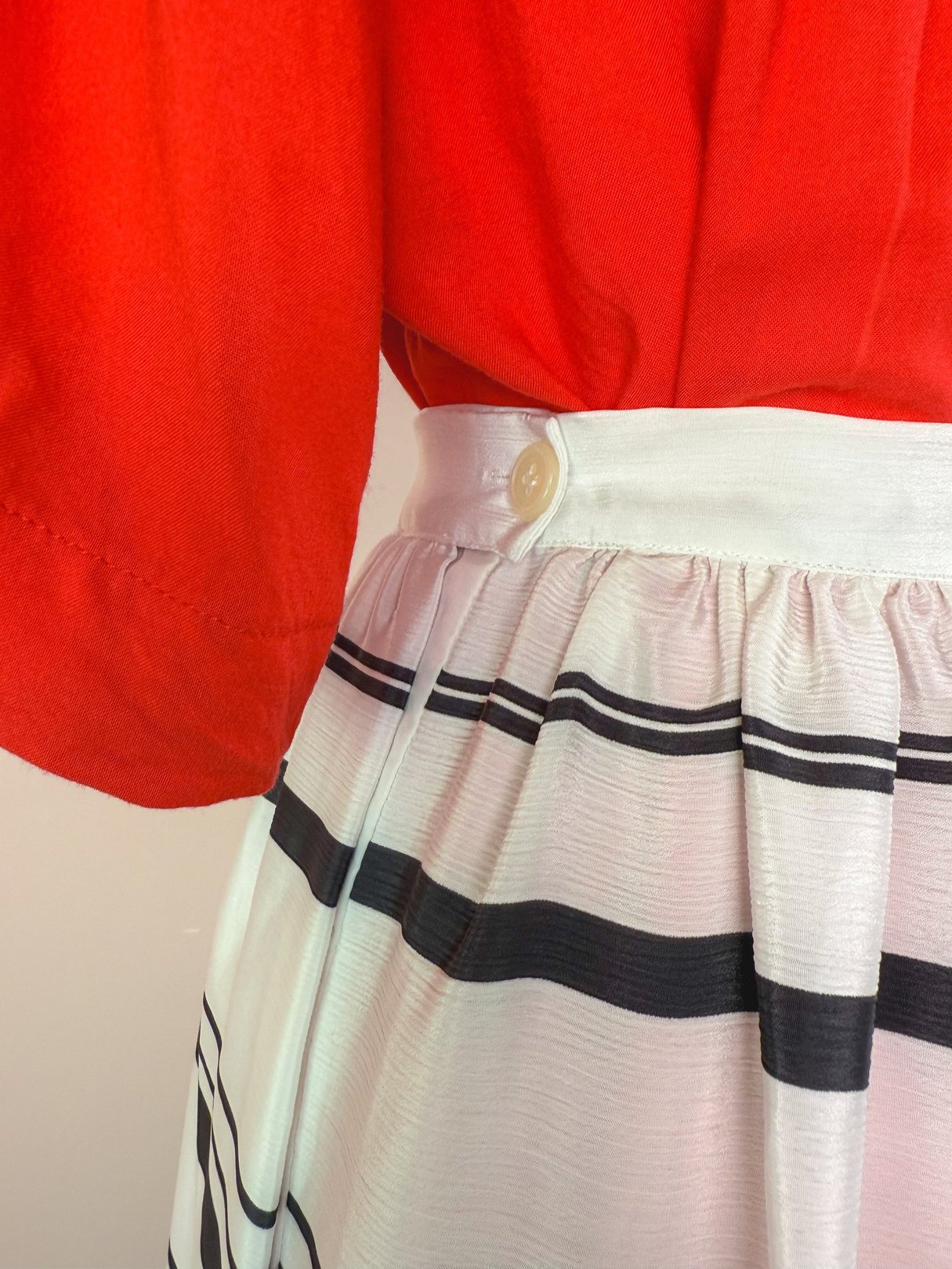 1970s women's white skirt featuring a button detail and black stripes.