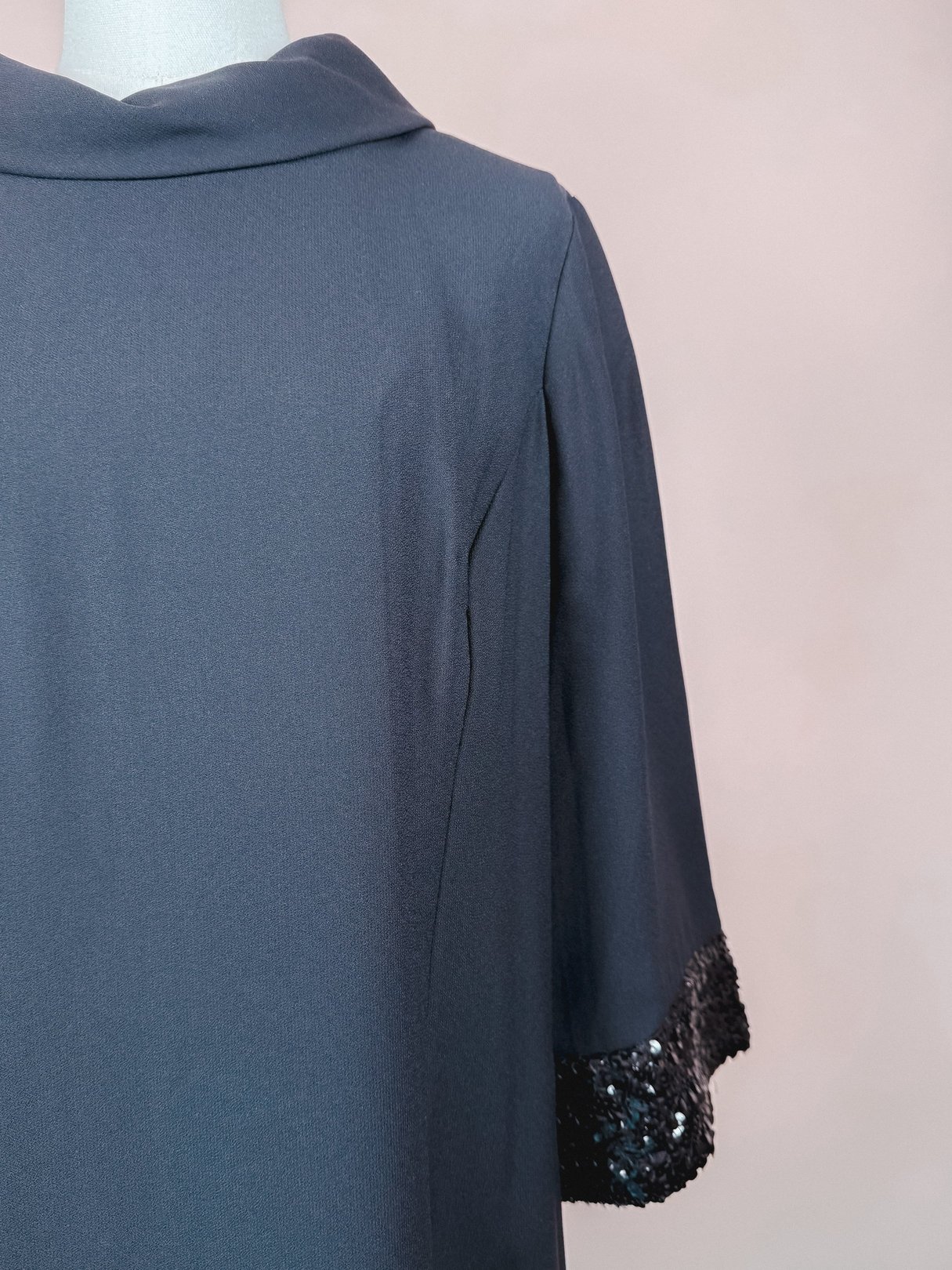 A black 1960s women's dress featuring a collar and short sleeves with sequin embellishments at the cuffs.