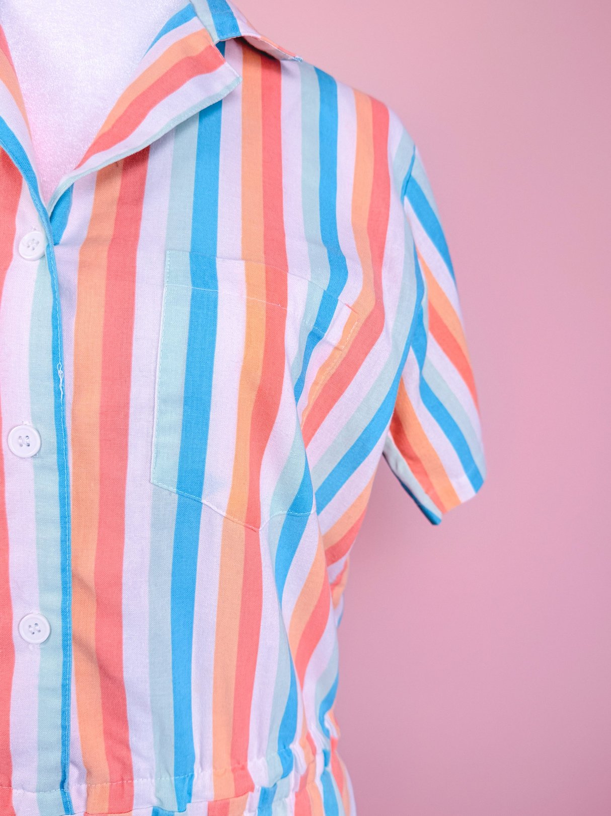A blue, striped women's romper from the 1980s featuring short sleeves and a chest pocket.