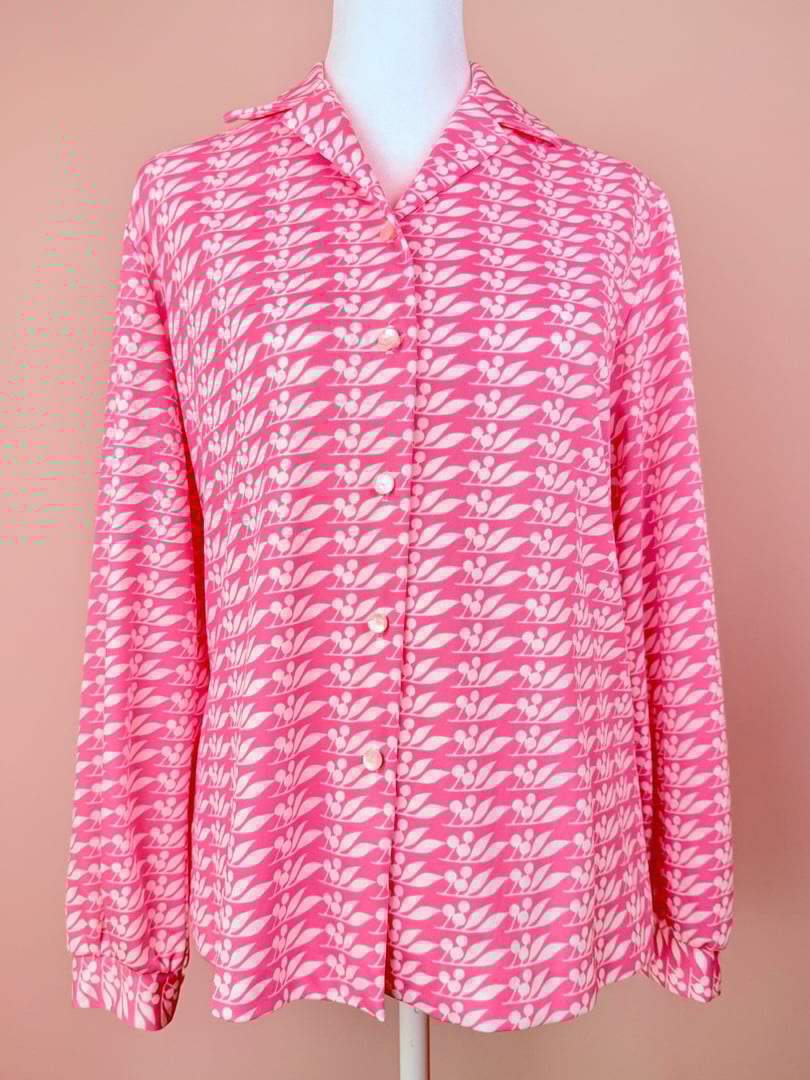 Pink 1970s women’s blouse featuring a cherry petal pattern and button-down front.