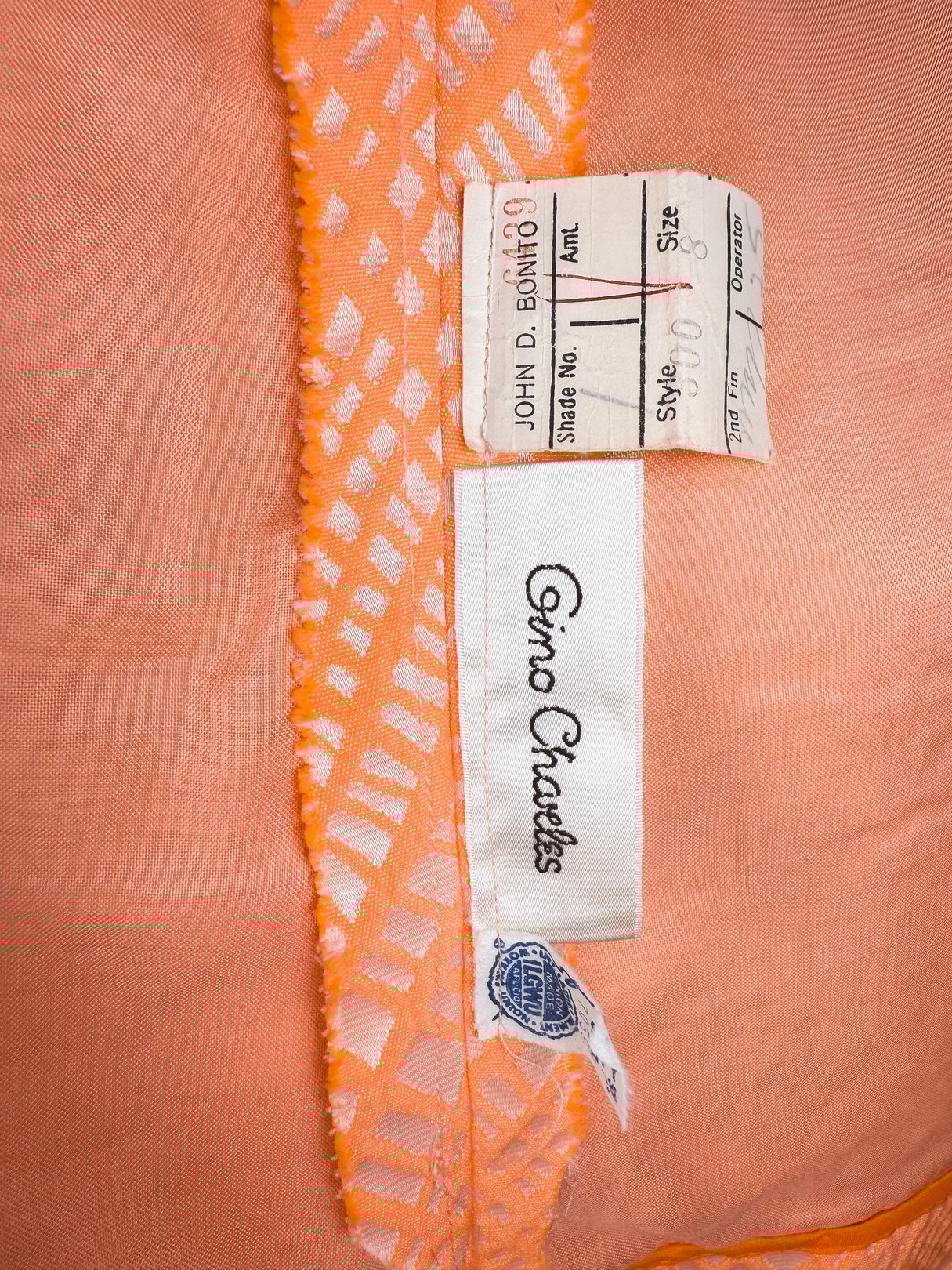 A 1960s women's dress in orange with a sparkling texture, featuring a label that reads "Gino Craeles.