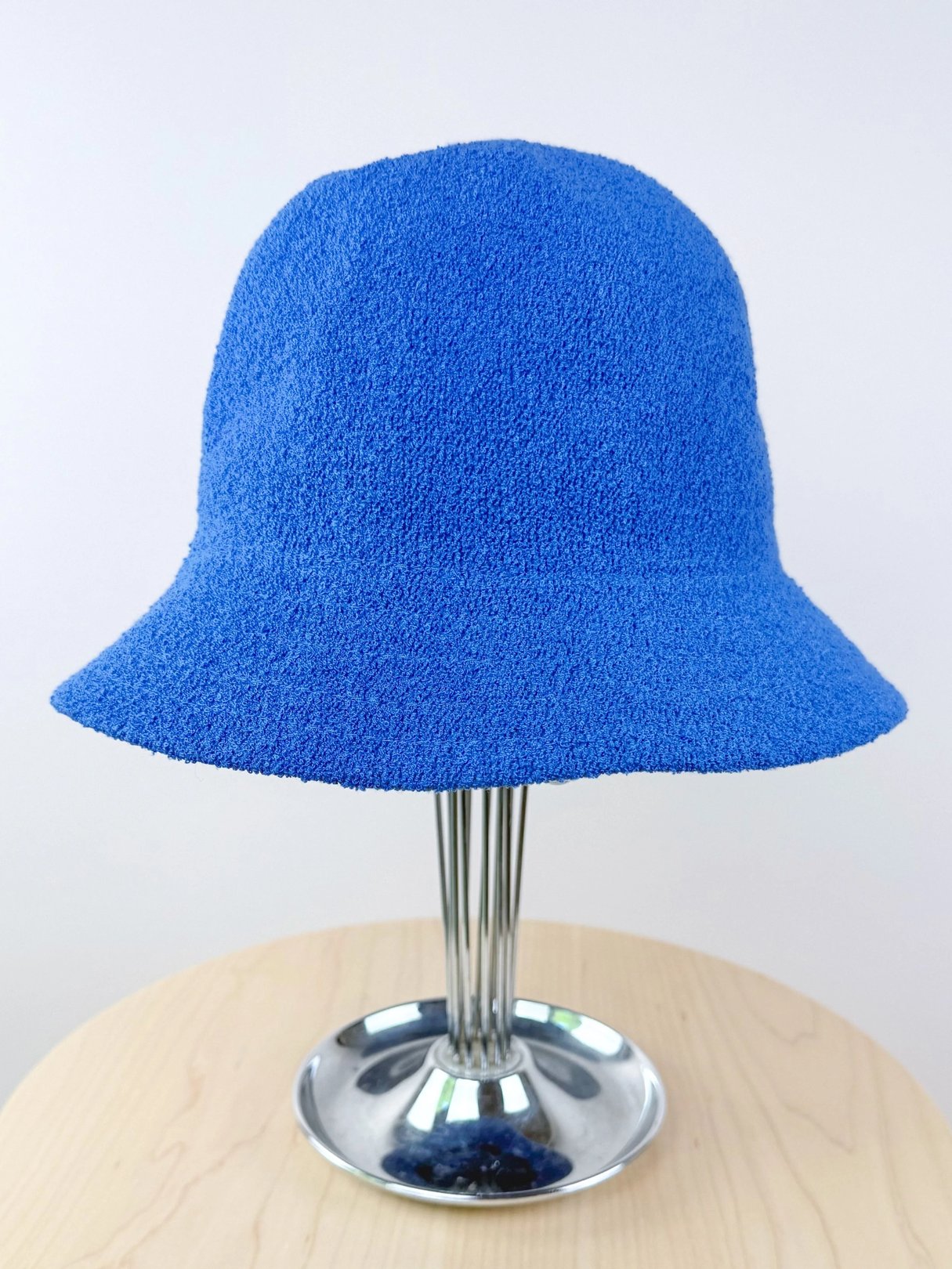 Blue textured bucket hat displayed on a silver stand.