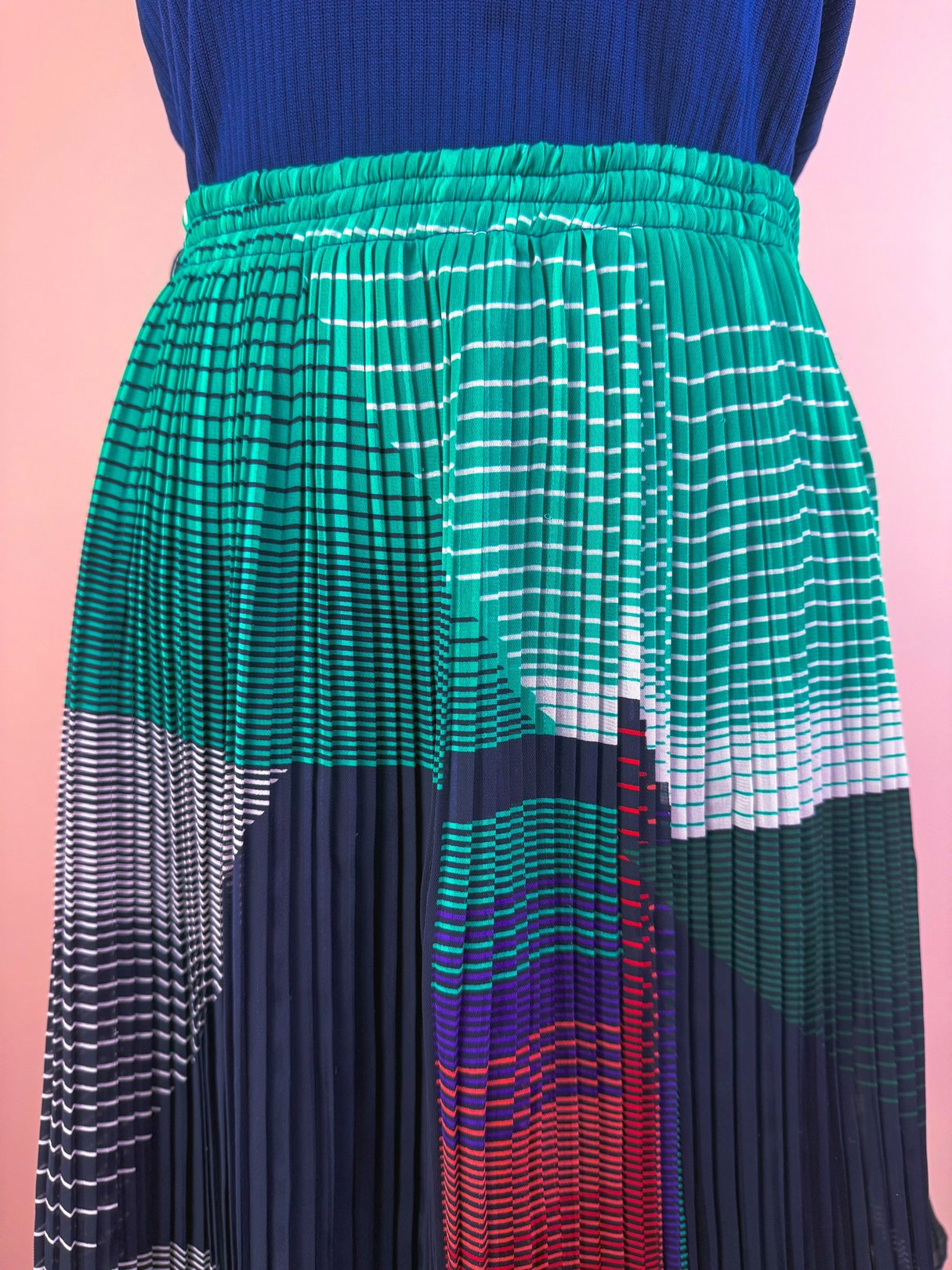 Green pleated skirt featuring a geometric pattern in various colors, designed for women and inspired by 1970s fashion.