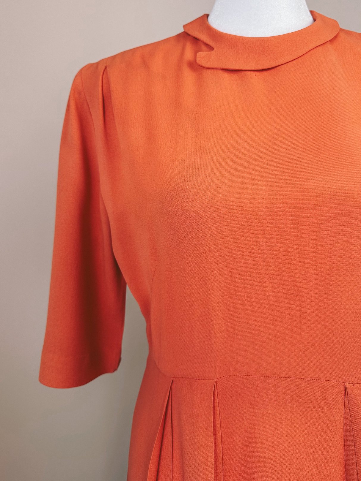 Coral 1940s women's recital dress featuring a high neckline and short sleeves with pleated detailing.