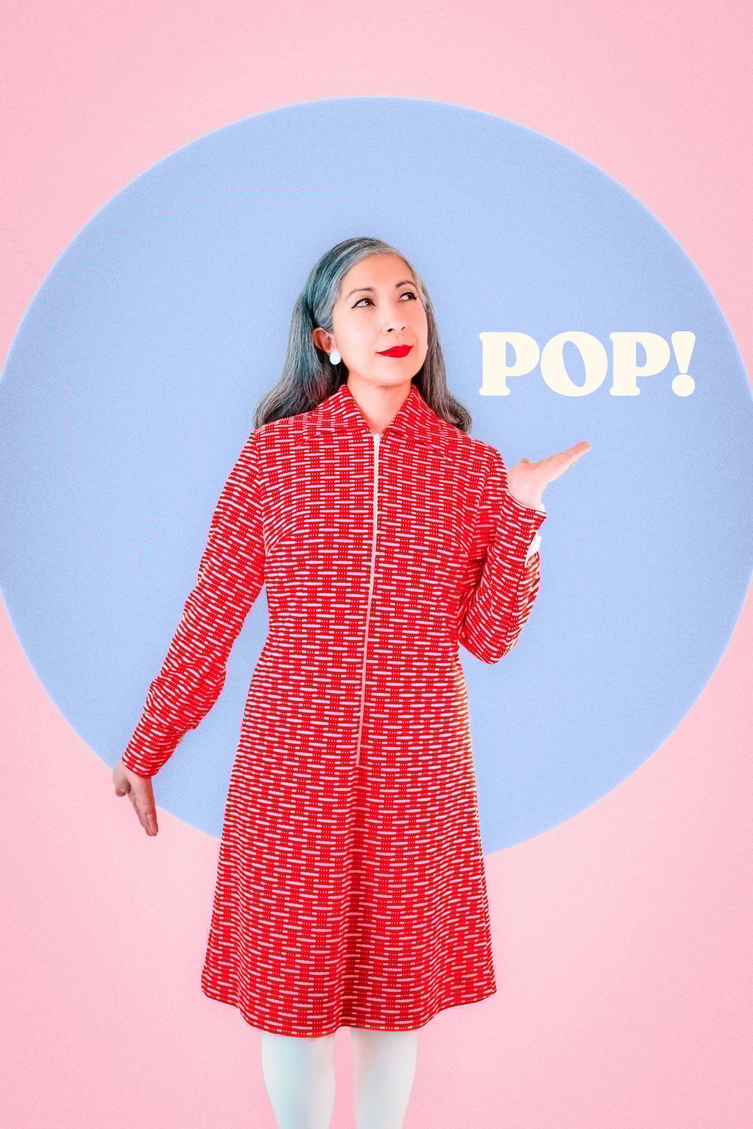 A woman wearing a red patterned coat stands against a pastel background, playfully gesturing with one hand and smiling as the word "POP!" appears next to her.