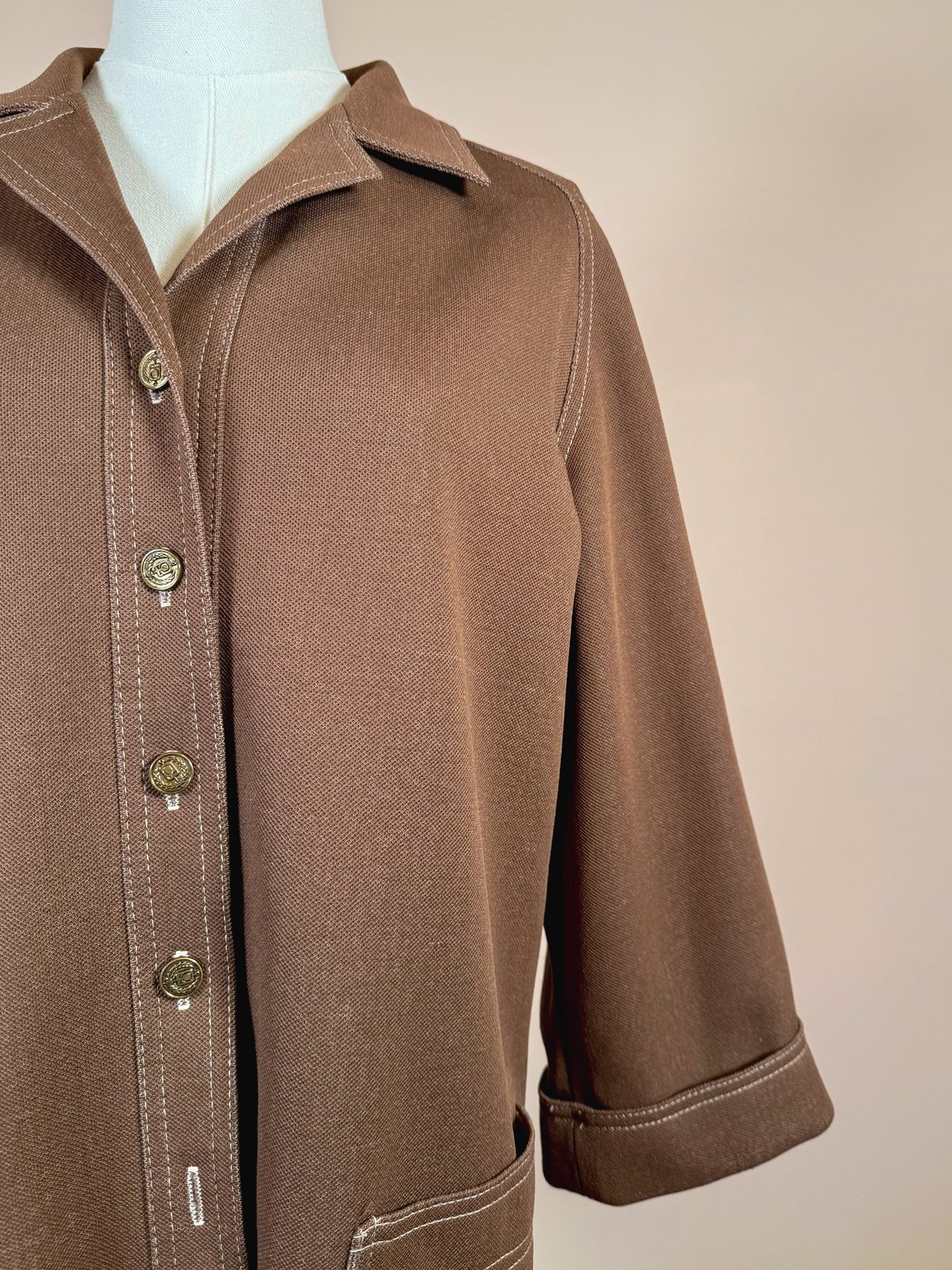 Chestnut brown women's jacket from the 1960s featuring a collared neckline, button closure, and rolled cuffs.