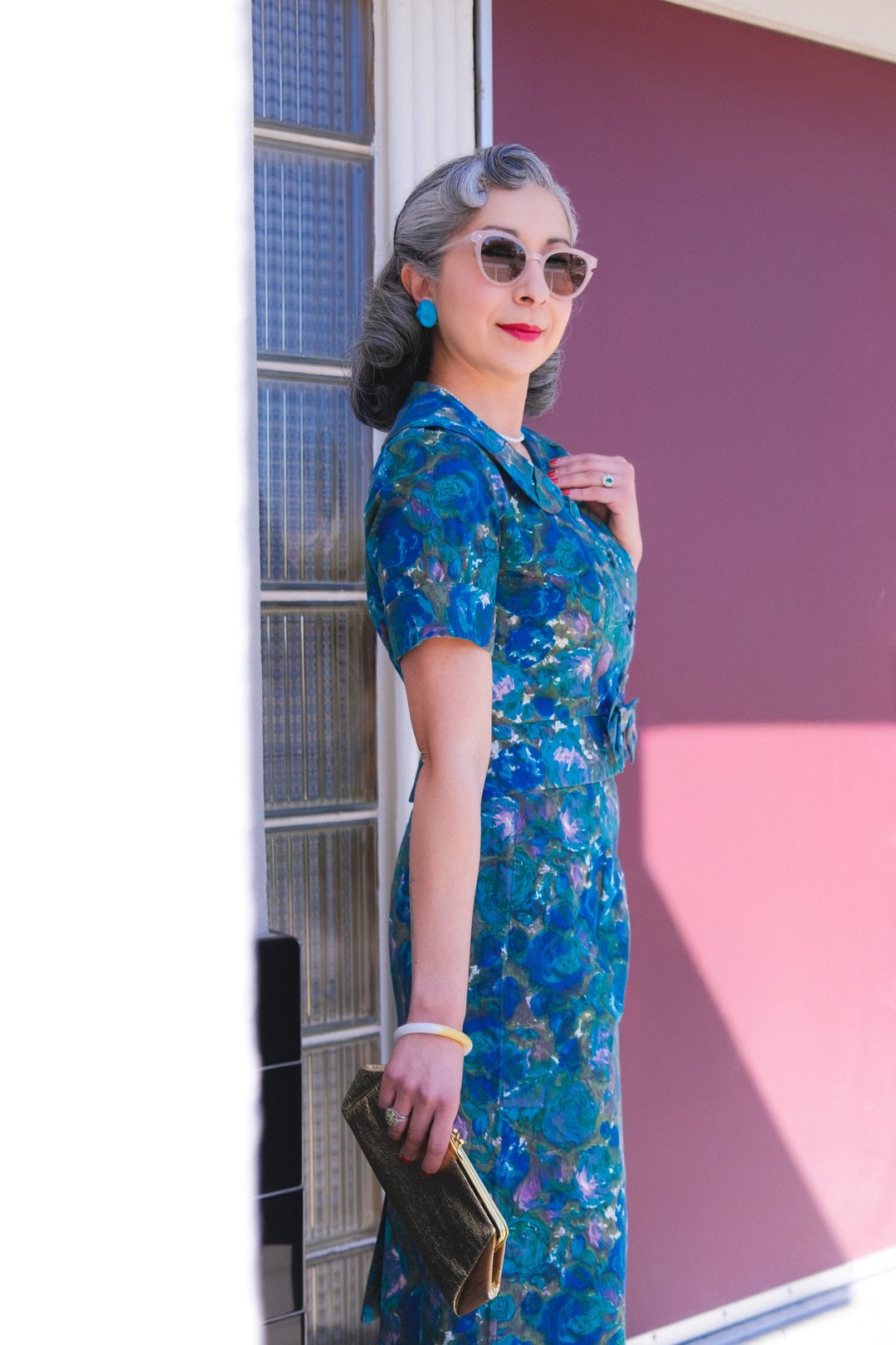 Women’s 1950s Coastal Flowers skirt set in blue, featuring a floral pattern, worn with sunglasses and a clutch.
