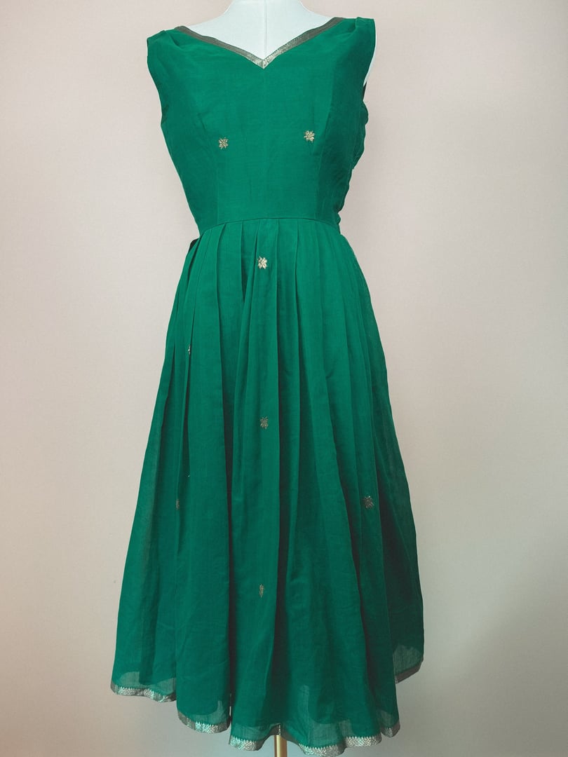Green 1950s-style dress featuring a starburst design with embellishments on the bodice and skirt.