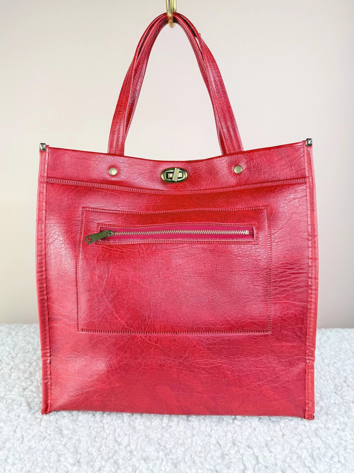 Red leather tote bag with a front zip pocket and two handles.