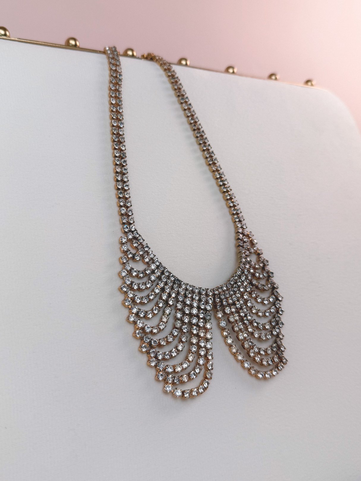 A gold collar necklace with sparkling rhinestones in a cascading design, reminiscent of 1970s jewelry.
