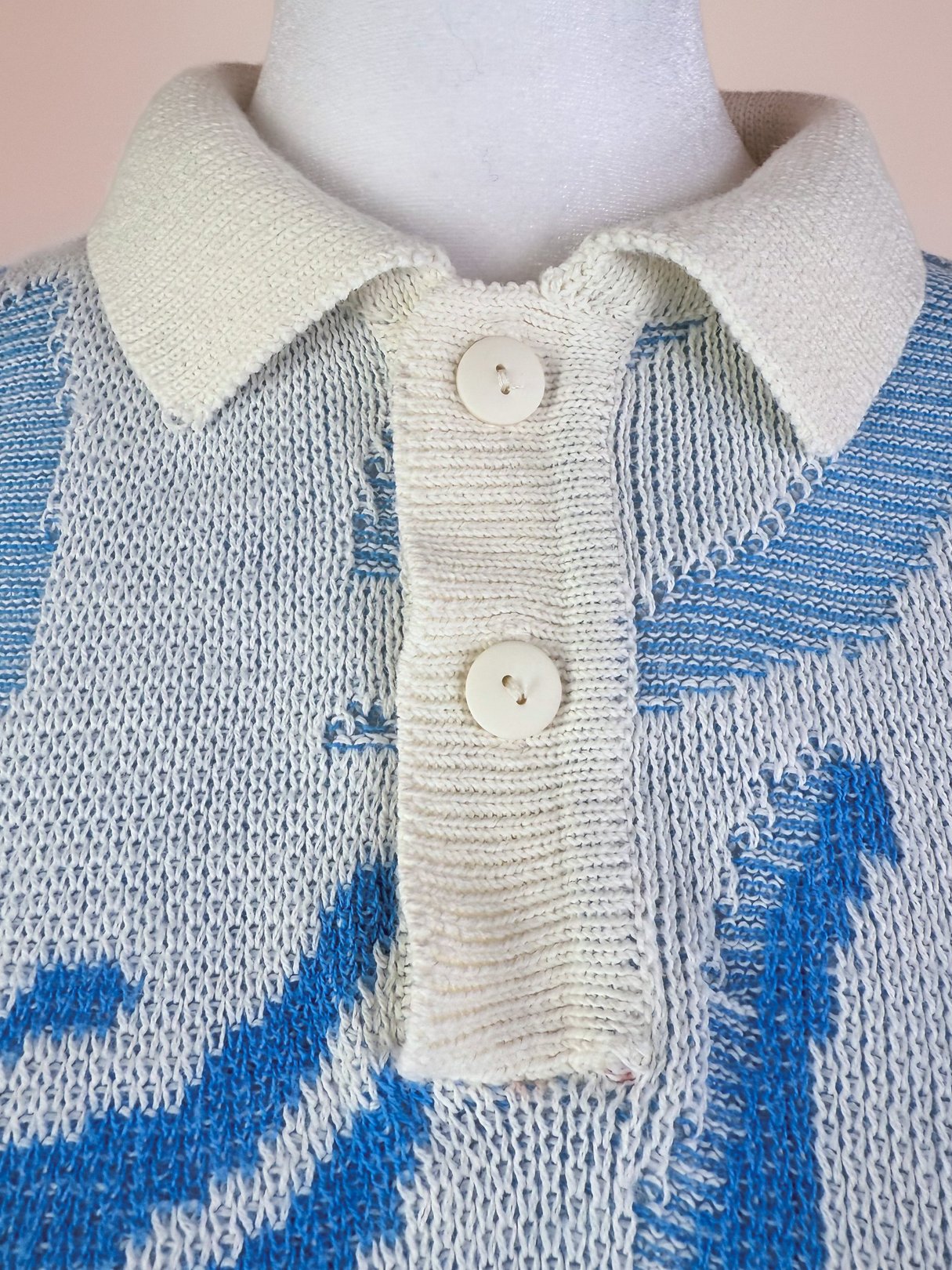 White women's 1980s knit polo sweater with a blue pattern and two buttons at the collar.