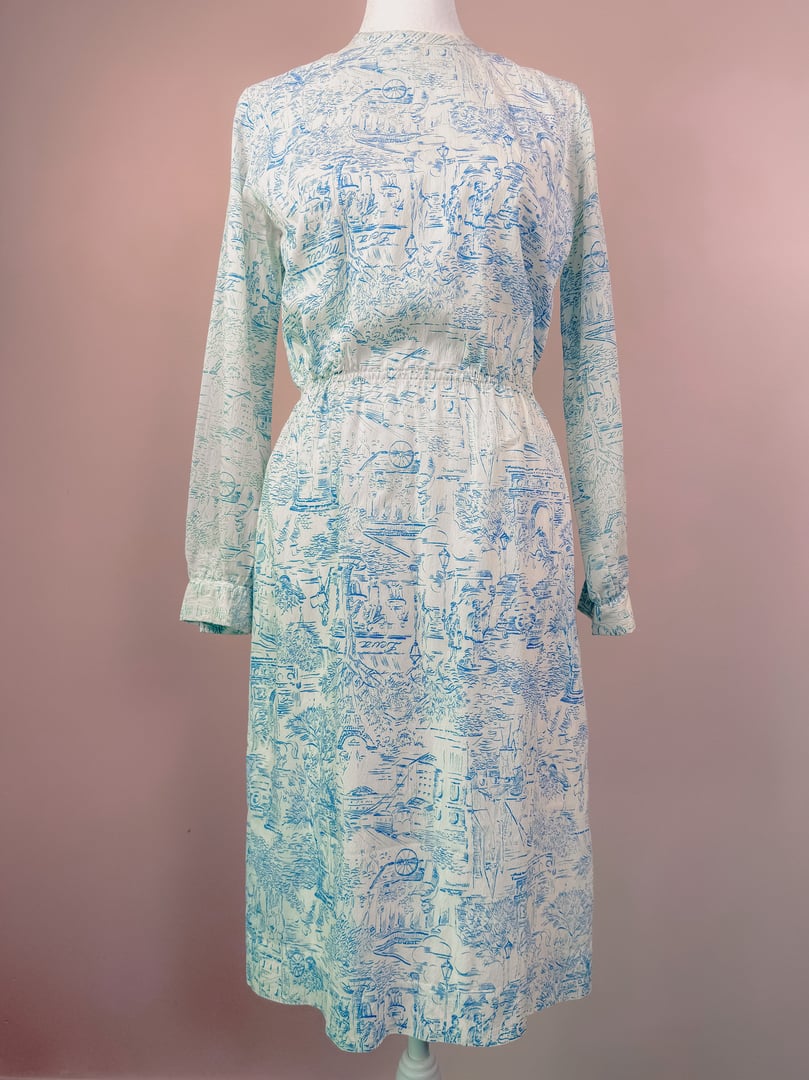 A blue 1960s women's dress featuring a Paris-themed montage design with long sleeves and an elastic waist.
