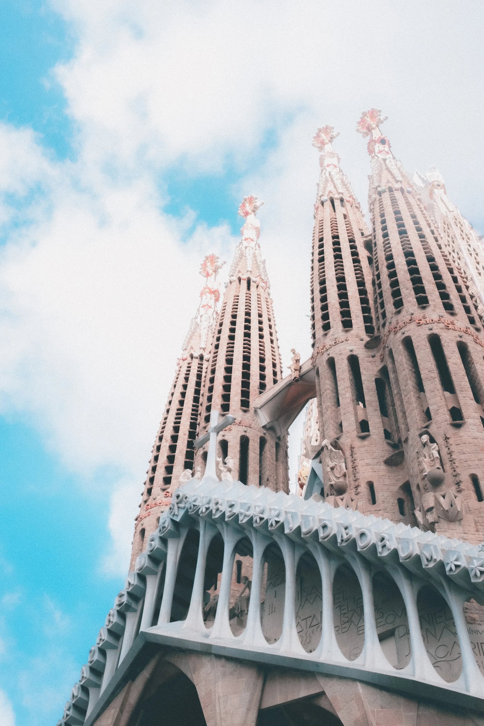 The towering spires of the Sagrada Família rise against a blue sky.