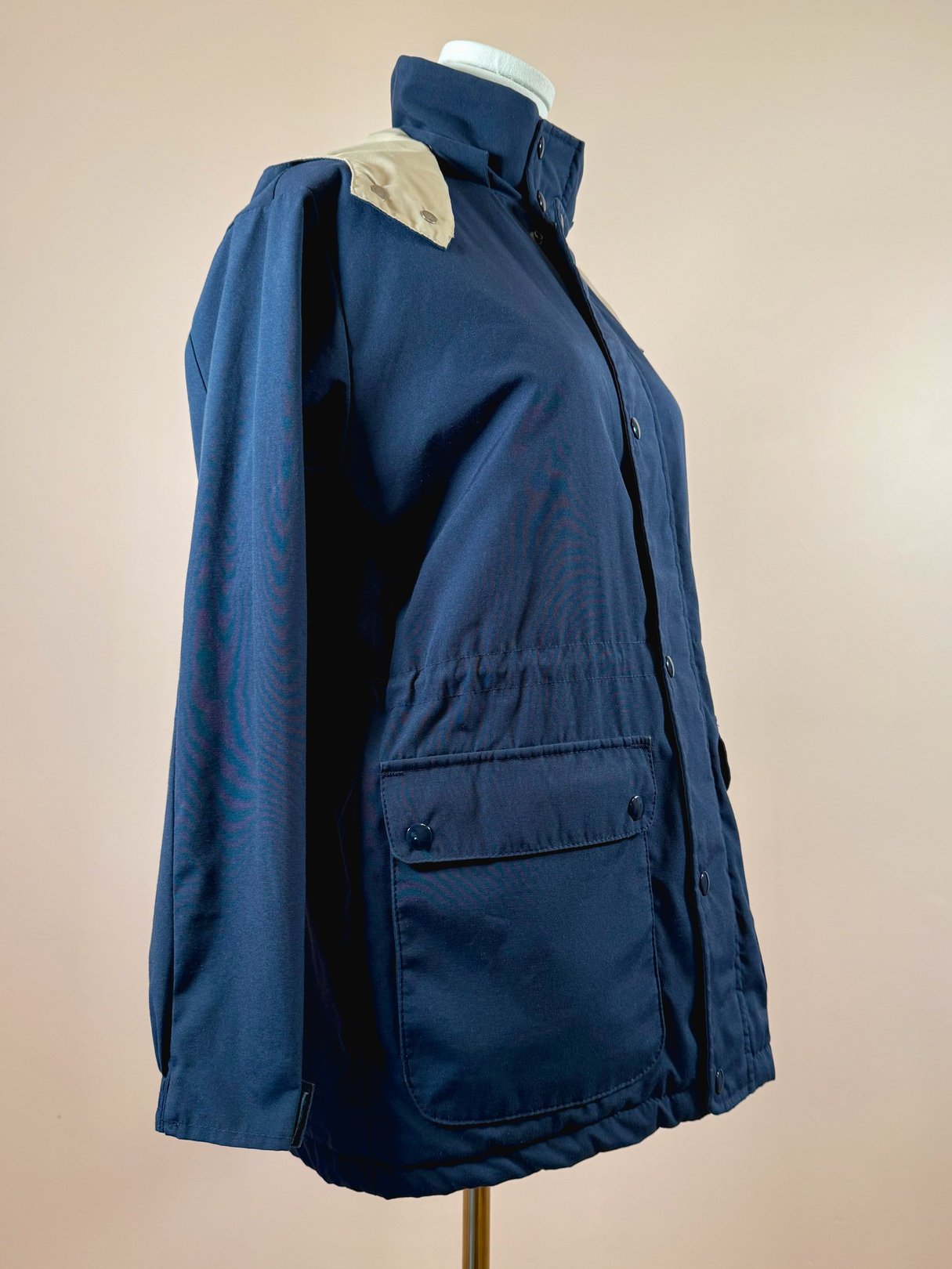 Navy blue women's utility field coat from the 1970s featuring a shoulder patch and front pockets.