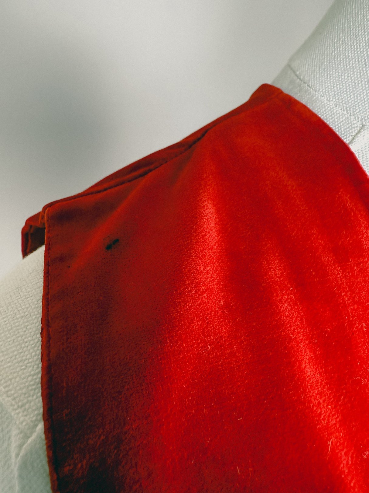 Red velvet vest with a sleek design and 1970s style, featuring a collar and visible sheen.