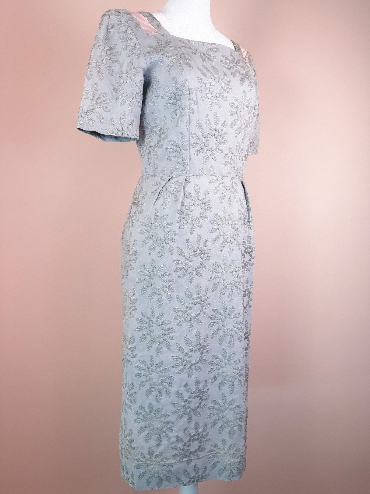 Slate blue 1950s women's bow dress featuring textured floral design and satin details on the shoulders.
