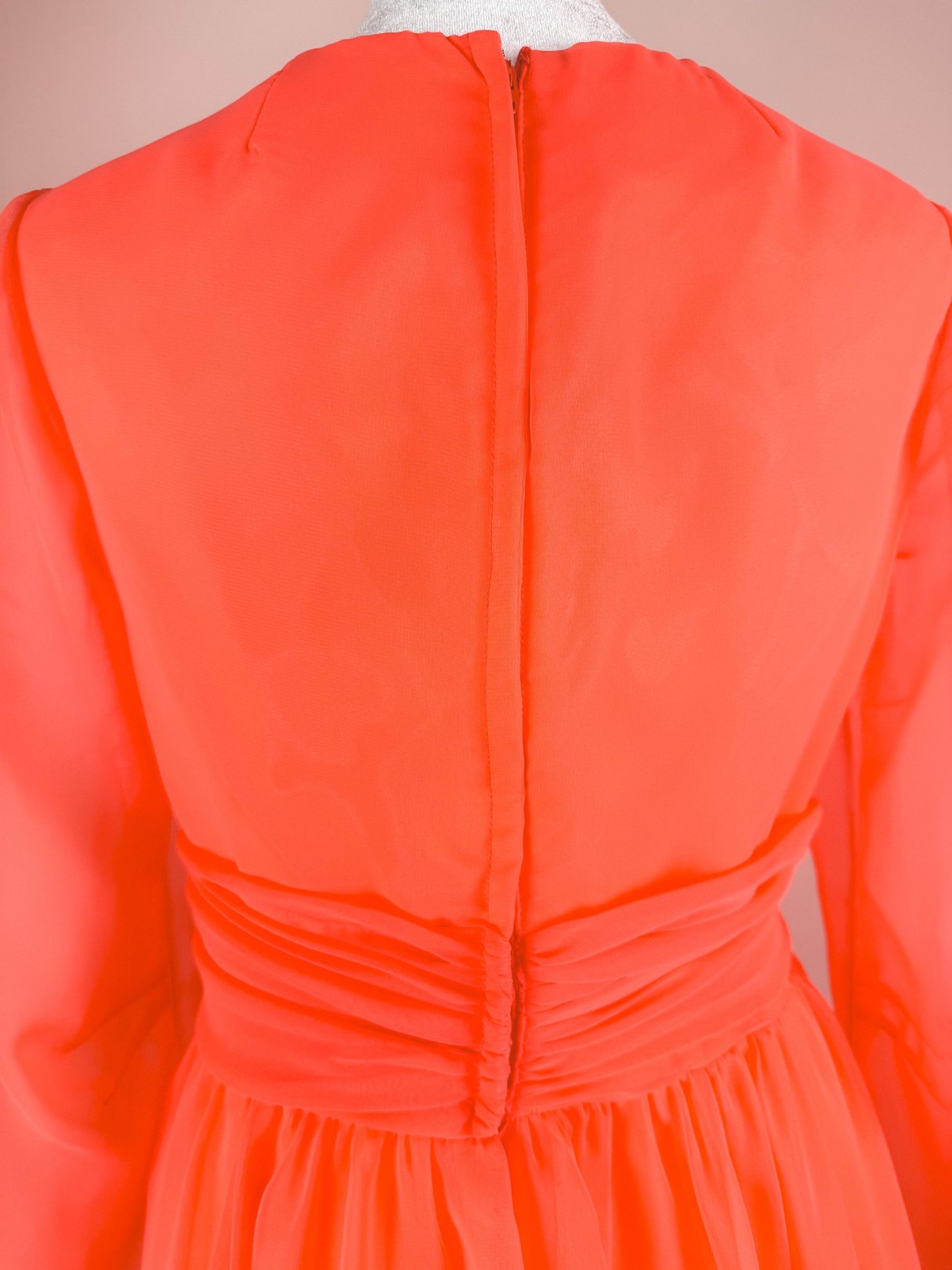 Coral Soirée Dress featuring a high neckline, long sleeves, and ruching at the back, characteristic of 1960s women's fashion.