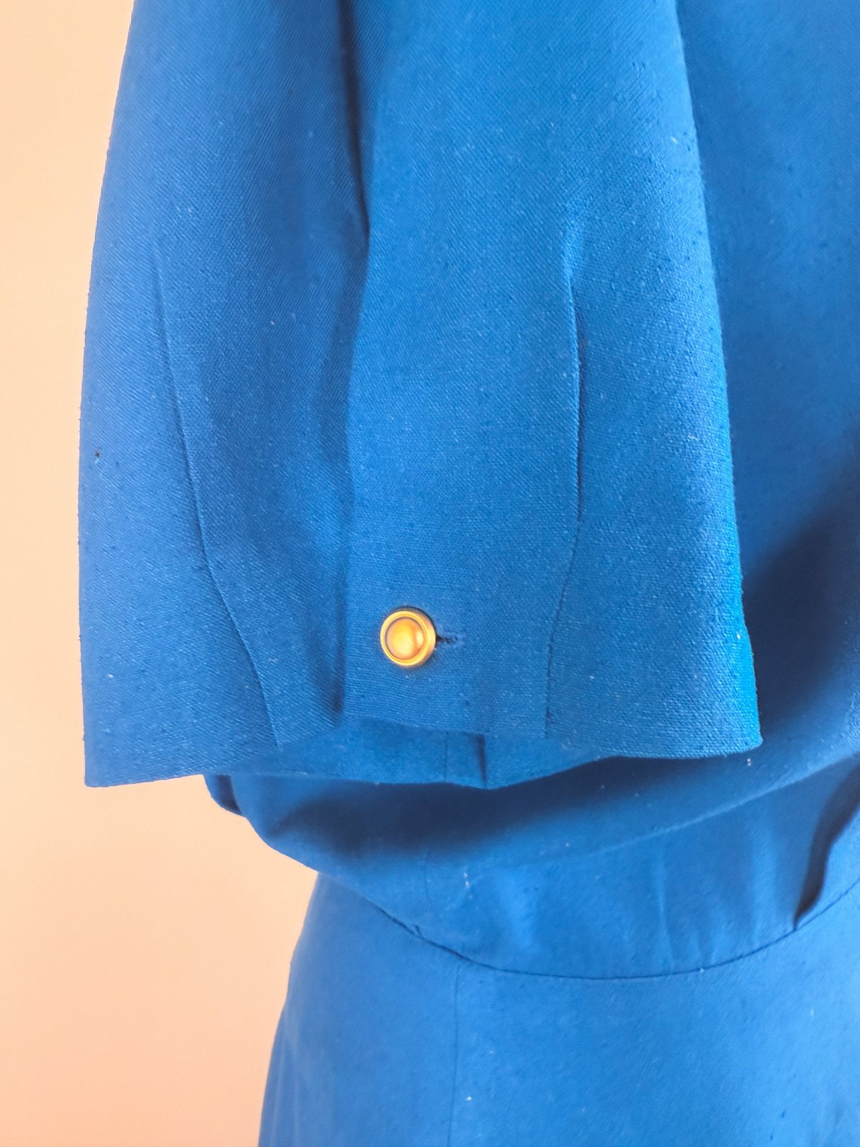 Cerulean blue 1980s women's dress featuring a short puff sleeve with a gold button detail.