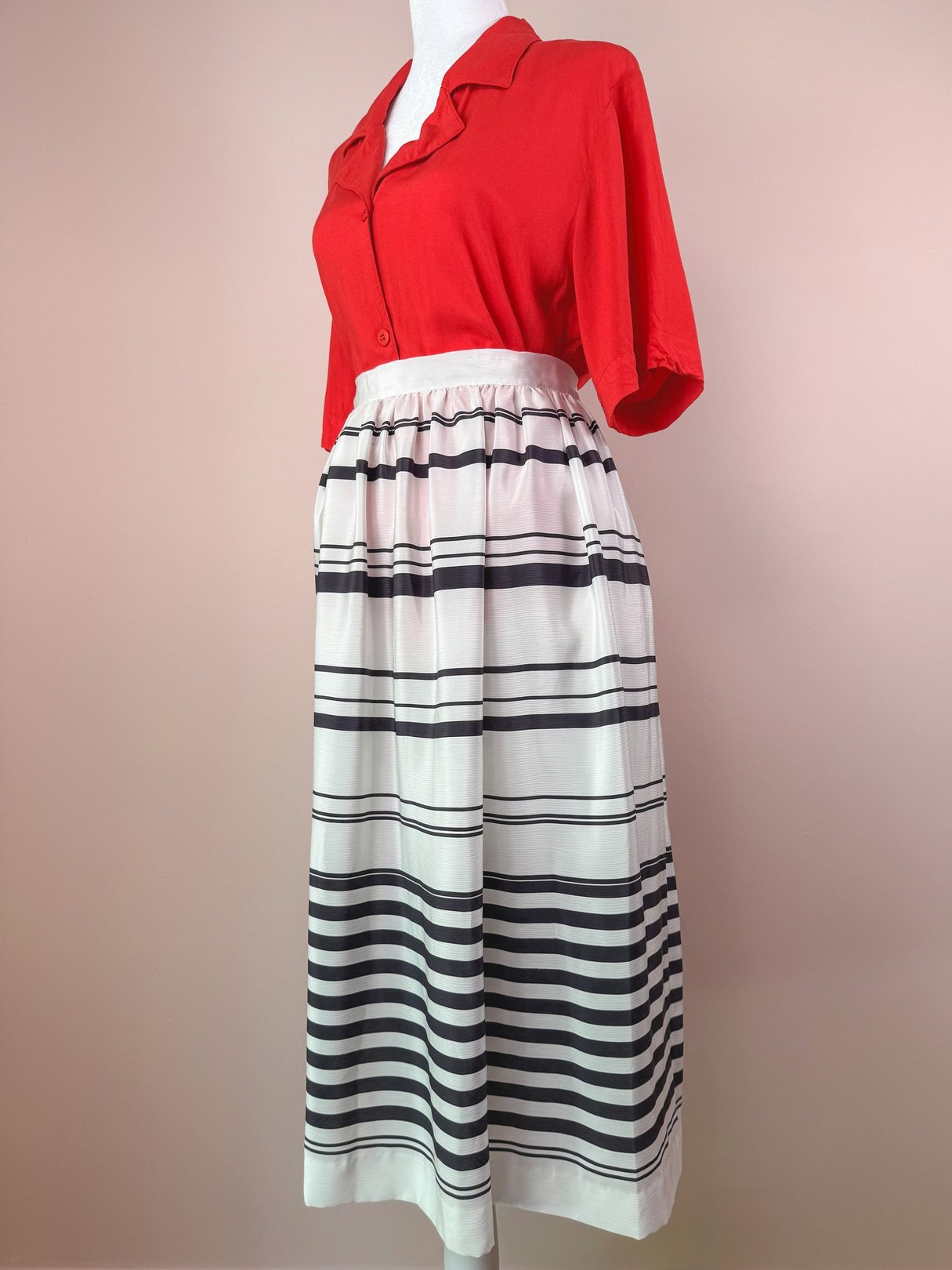 A white 1970s women's skirt with horizontal black stripes, featuring a fitted waistband and side pockets.