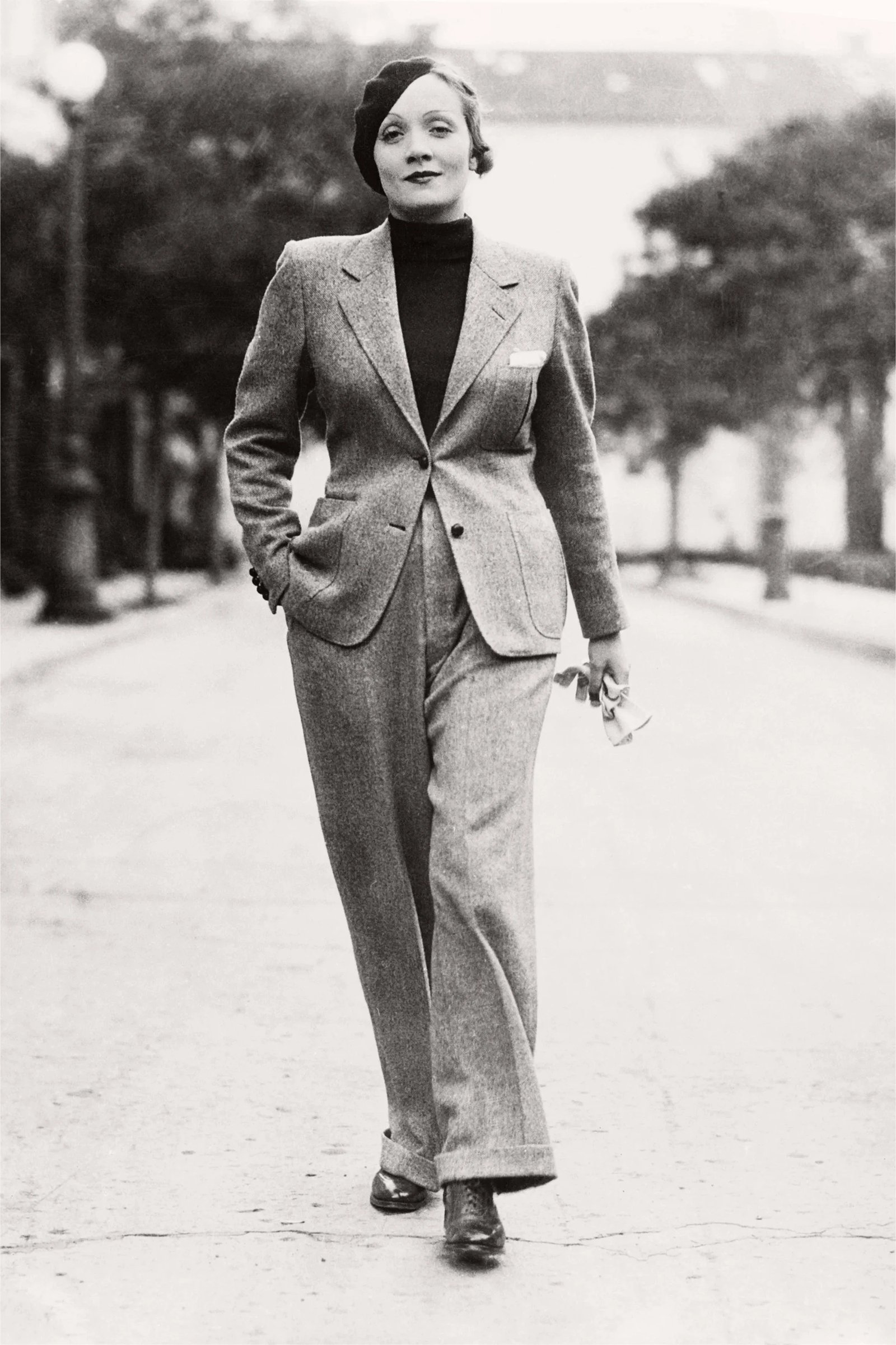 A woman confidently walks down a street wearing a tailored gray suit and heels.