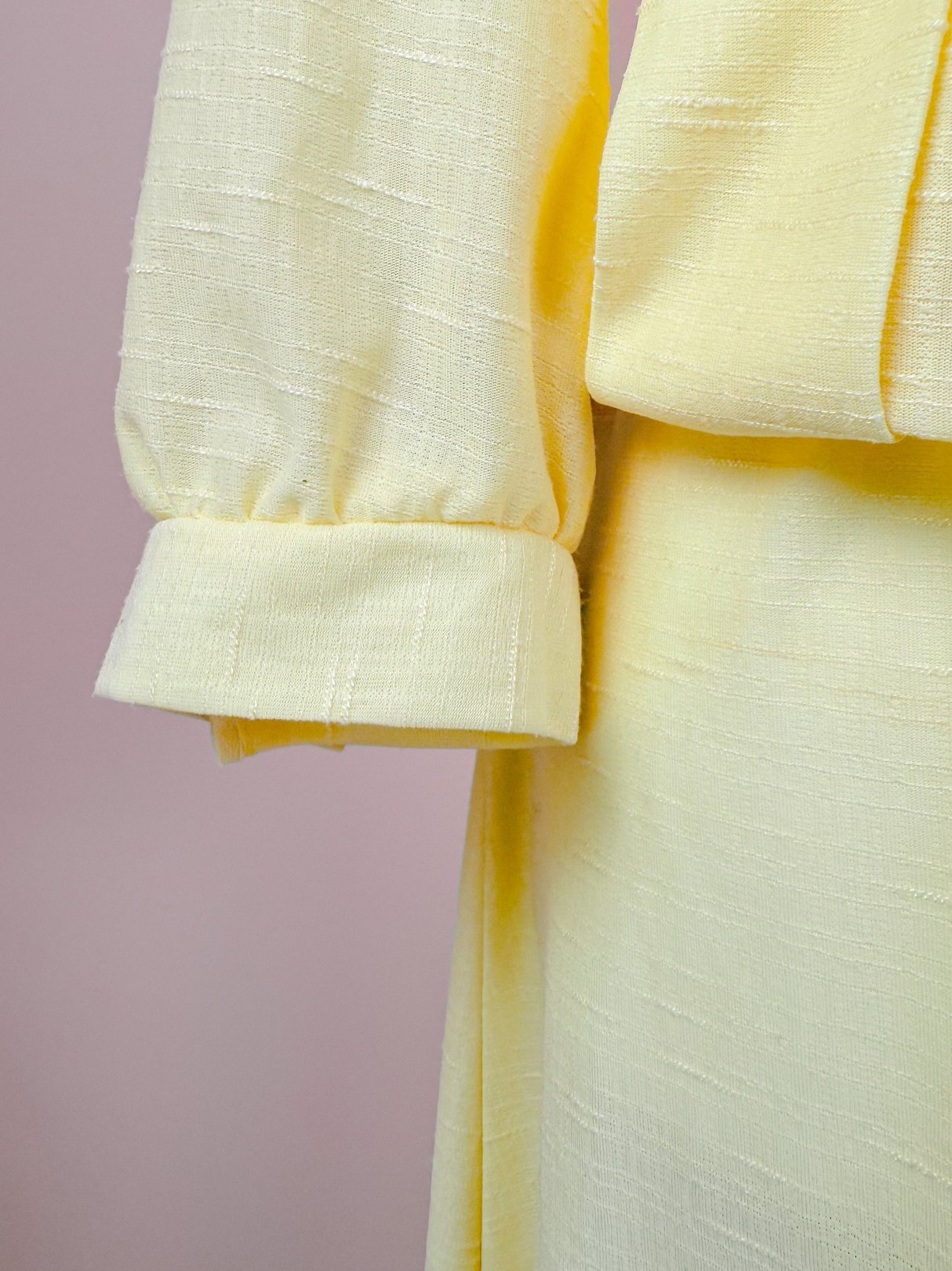 The Lemon Chiffon Dress features a soft yellow fabric with a textured finish and puffed sleeves.
