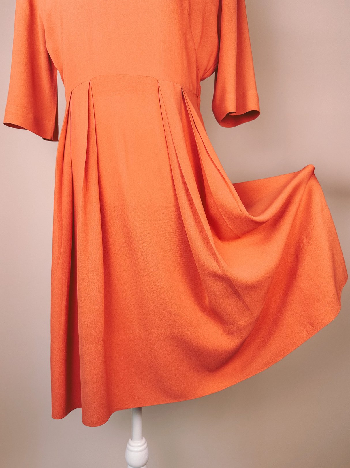 1940s coral dress featuring short sleeves and a pleated skirt, suitable for women.