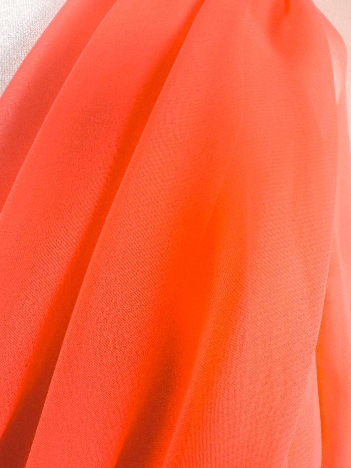 Coral Soirée Dress featuring a flowing coral fabric with soft pleats, indicative of 1960s women's fashion.