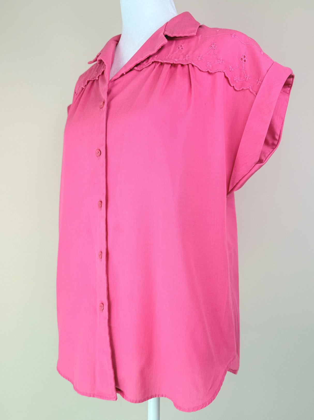 A loose-fitting, short-sleeved pink top featuring a button-down front and decorative lace detailing, styled for women and reflective of the 1980s era.