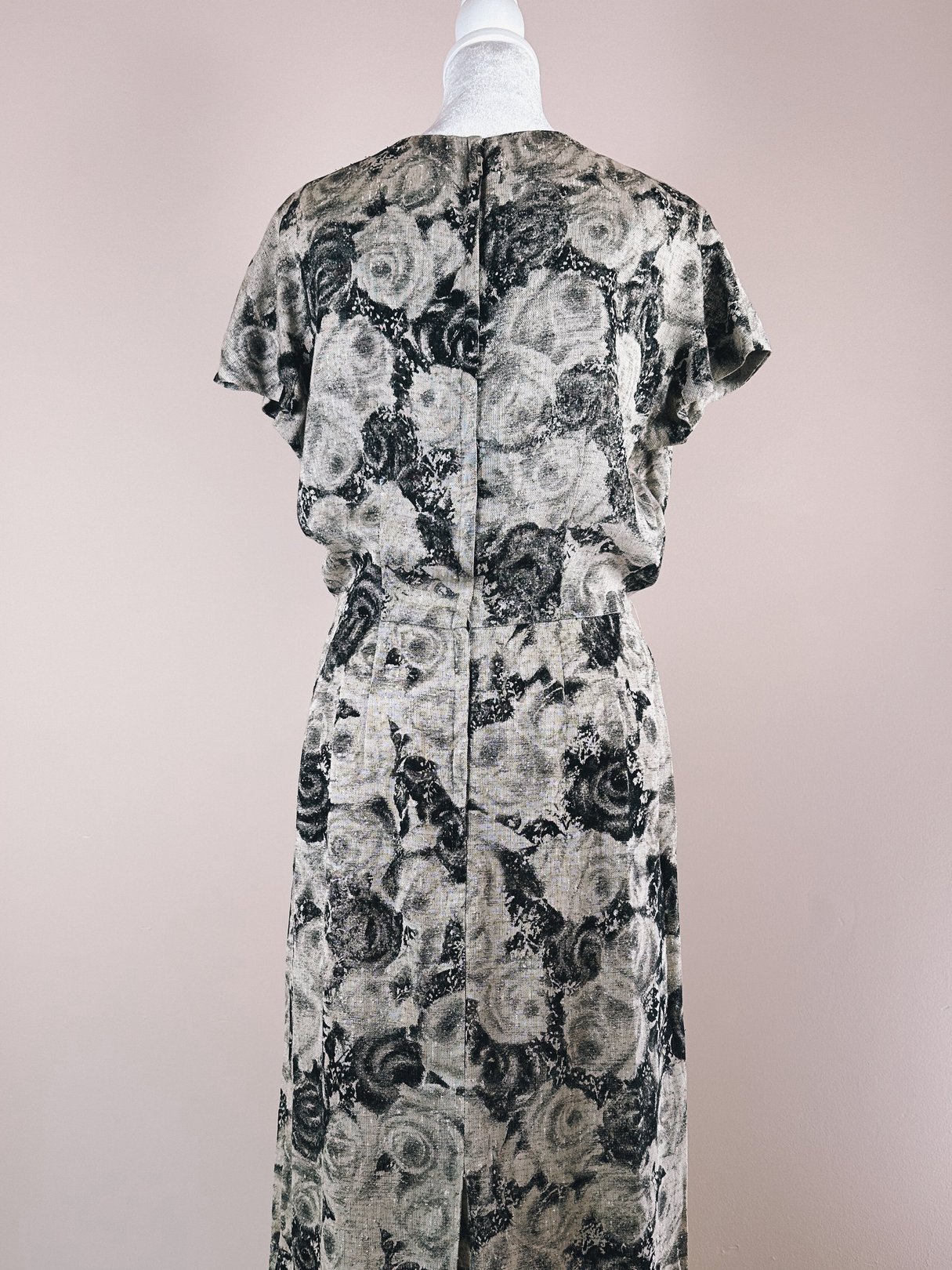 Back view of a women's 1950s black and cream rose dress featuring a floral pattern.