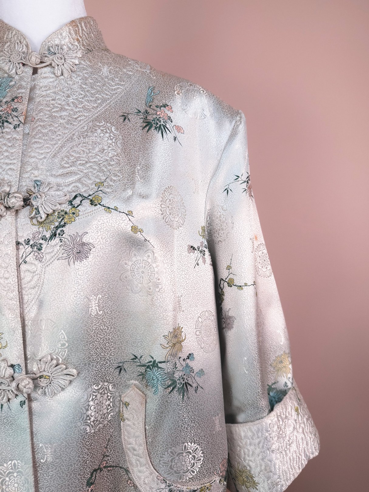 Silver 1970s women's Harmony Silk Cheongsam Coat featuring floral patterns and ornate detailing.