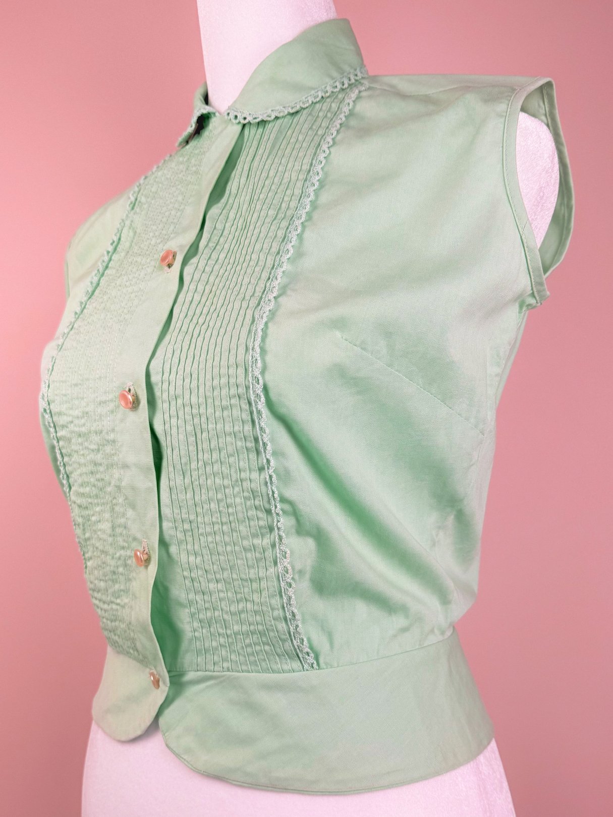 1950s mint green fitted blouse with a button-up front and pleated detailing.