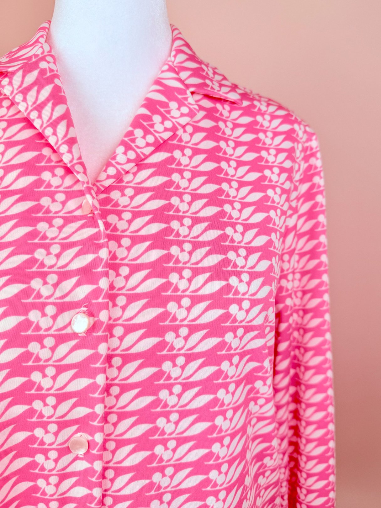 Pink 1970s women’s Cherry Petal Blouse featuring a leaf and petal pattern with a collared neckline and button closure.