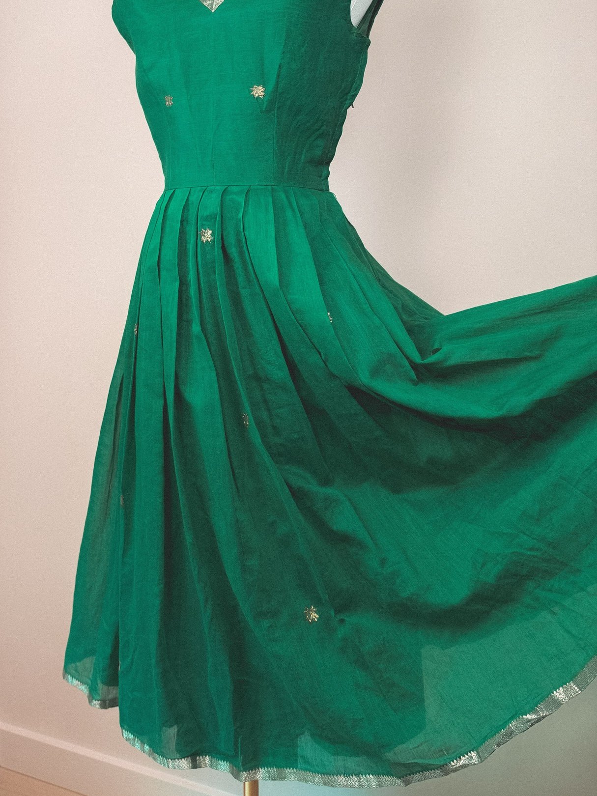 A green 1950s-inspired dress with a starburst pattern and pleated skirt.