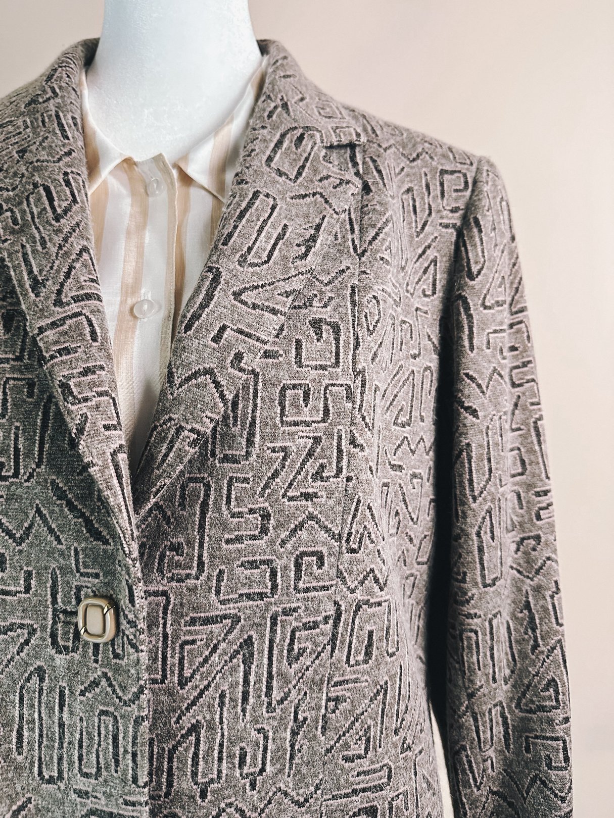 Pink geometric blazer for women featuring a patterned design, typical of 1980s fashion, displayed on a mannequin.