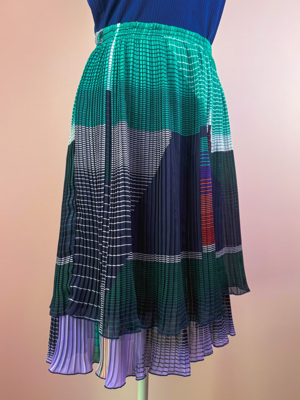 Pleated green skirt with multicolored patterns and a flowing silhouette, inspired by 1970s fashion for women.