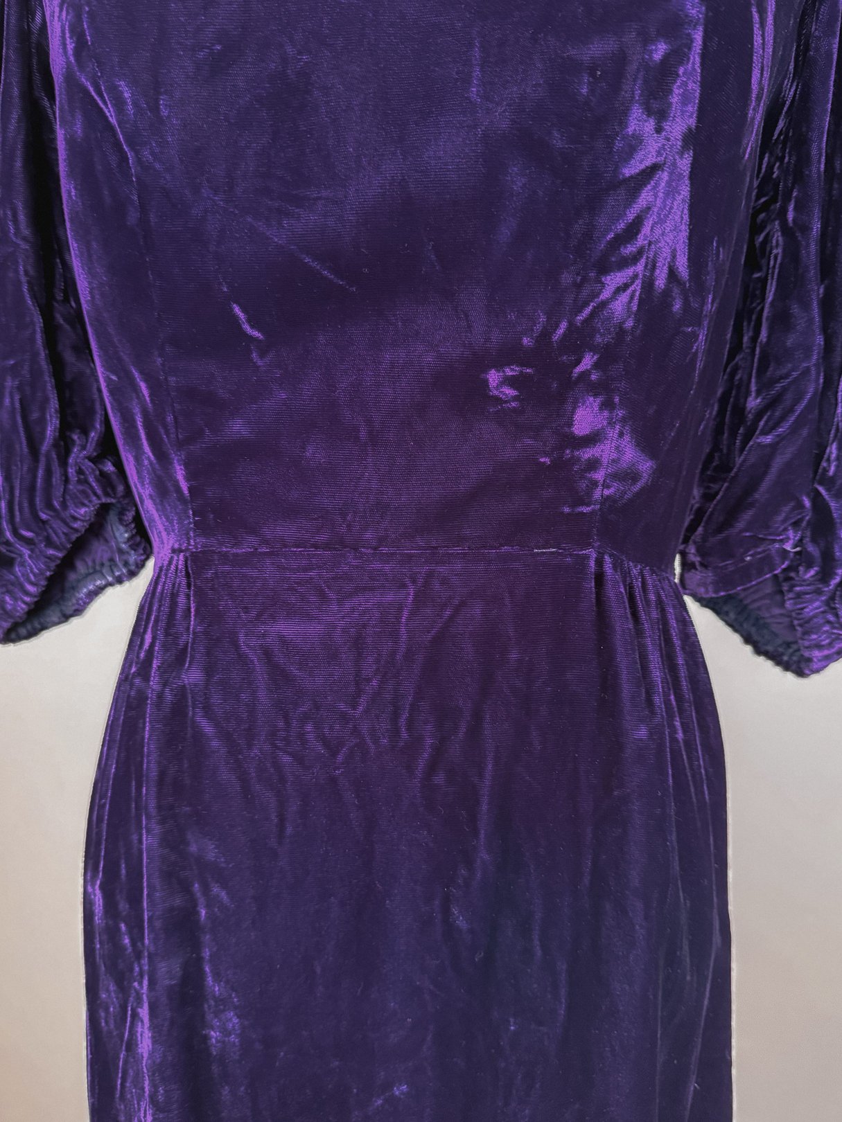 Purple velvet dress with puffed sleeves and a fitted waist, reflecting 1960s fashion.