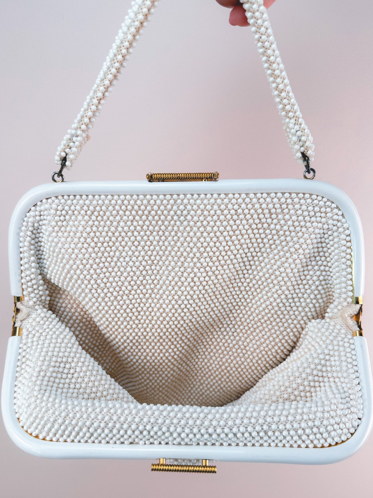 Cream white handbag with a textured bead design and a structured frame, featuring a pearl-like handle.