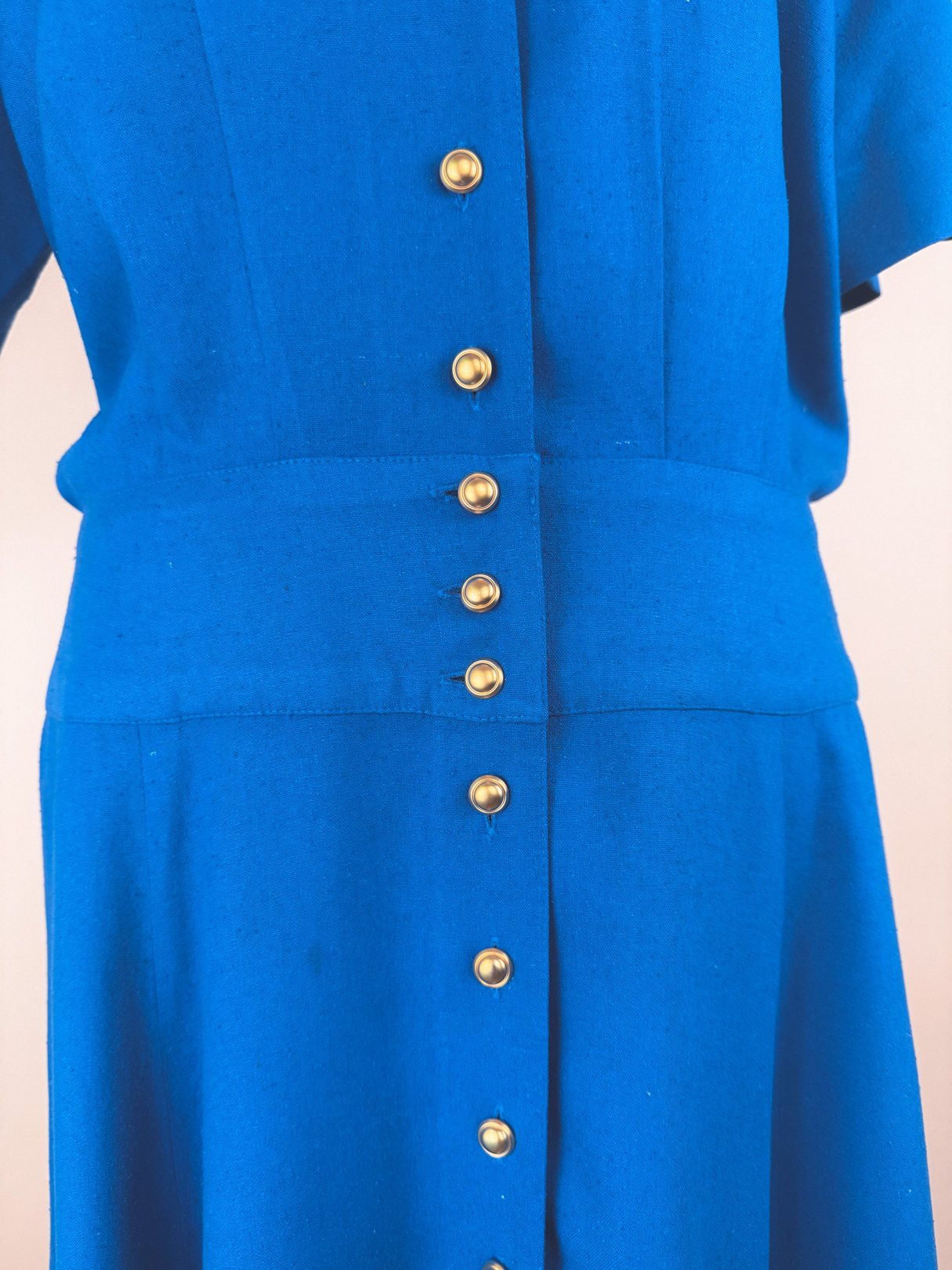 Cerulean blue 1980s women's dress featuring a button-down front and a structured waist.